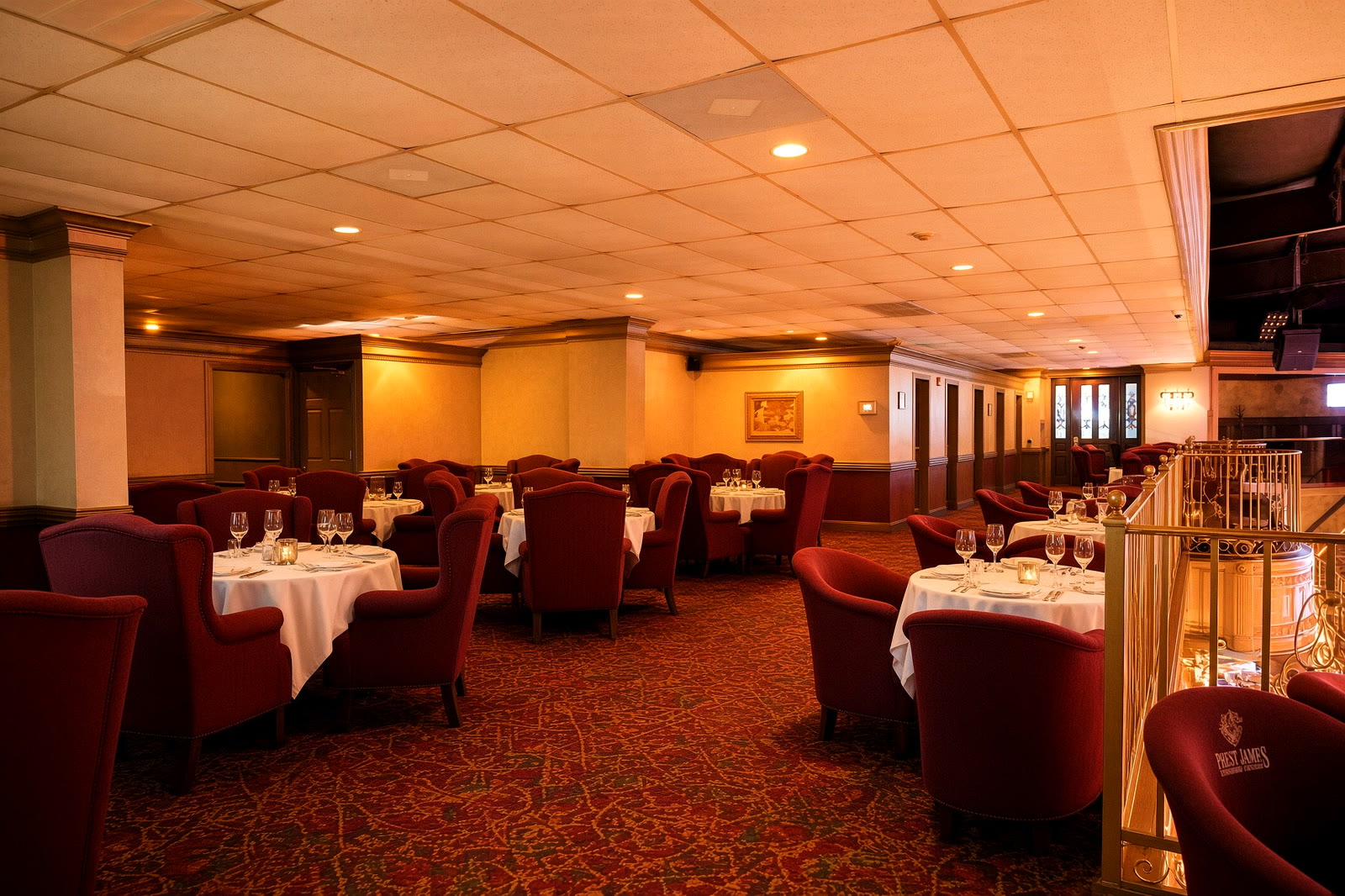 Upper dining at The St. James from the balcony — white linen, candles, gold rail